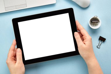 Mavi yüzeyde beyaz ekranlı yatay tablet bir bilgisayarı tutan ellerin görüntüsü. Düz yatıyordu