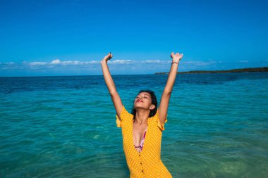 Kumsalda elleri açık mutlu bir kadın.
