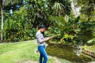 Ormanda cep telefonunu kontrol eden bir kadın.