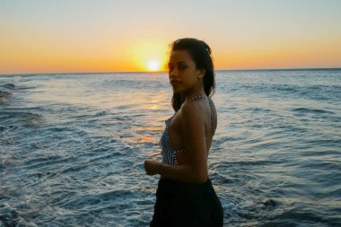 Altın rengi bir kadının arkasında güneş ışığıyla güzel bir gün batımı.