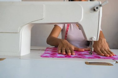 Terzide dikiş makinesi kullanan genç bir kadın..