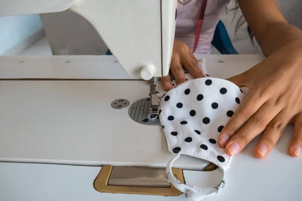 Evde oturan ve yüz maskesi takan terzinin yakın çekimi.