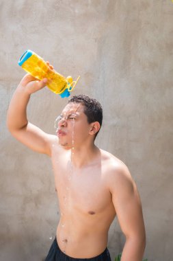 Evde antrenman yaparken serinlemek için kafasına taze su döken yorgun genç bir sporcu.