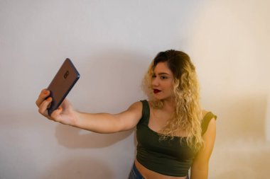 Makyajlı ve rujlu bir kız cep telefonuyla fotoğraf çekiyor.