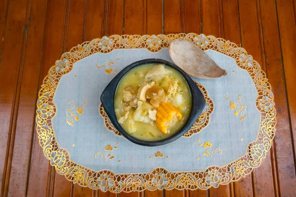 Colombian mondongo soup in a bowl with a wooden spoon on the eating table