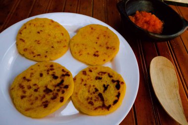 Kolombiya Hogao soslu (domates ve soğan pişirilmiş) beyaz bir tabakta arepas. Arepalar sarı mısır unundan yapılır ve geleneksel olarak Kolombiya ve Venezuela 'da yenir.