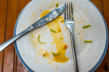 Tahta masada yedikten sonra çatal ve bıçakla dolu boş bir tabak. Boş tabağın üst görüntüsü, yemekten sonra kirli.