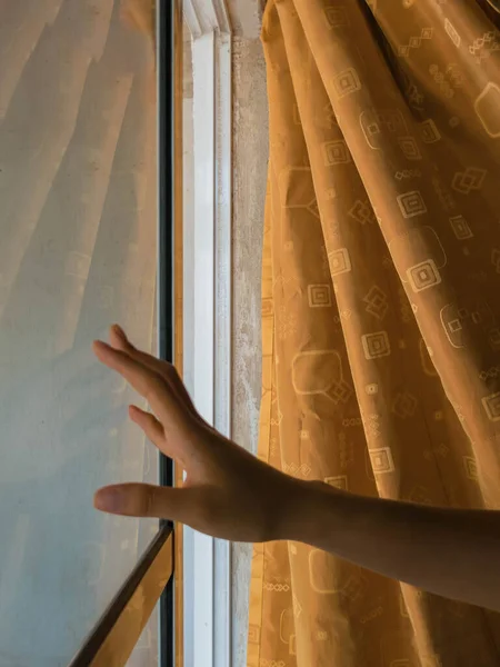 woman\'s hand touching the window at home