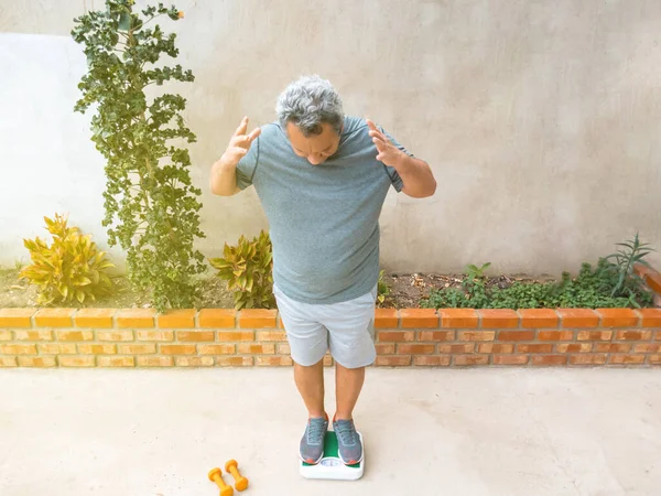 Kilo kaybı, zayıflama, sağlıklı yaşam tarzı ve insan konsepti. Kilolu bir adamın evde tartılması.