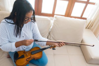 Genç bir Afrikalı kadın evde keman çalıyor.