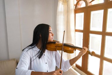 Kadın evde keman çalışıyor.