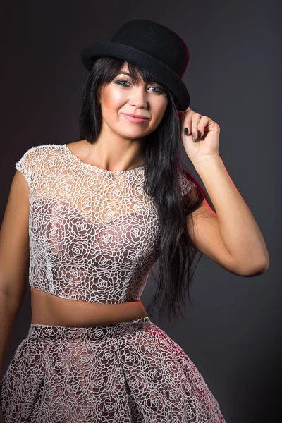 Belle femme dans un chapeau et une robe de dentelle sur fond noir Photo De Stock