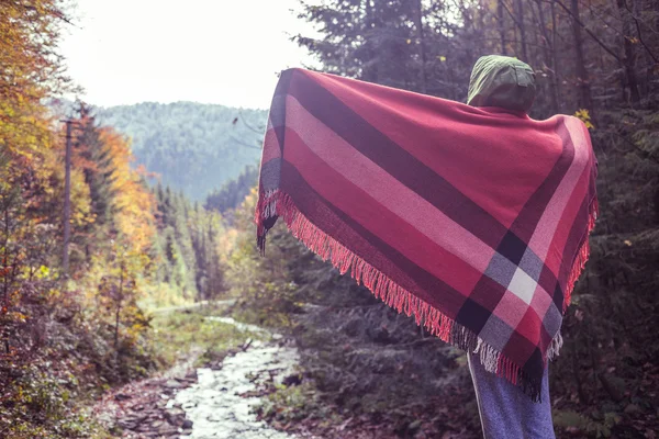 Beautiful girl in autumn forest in mountains wrapped in a plaid woolen blanket enjoy sunrise — Stock Photo, Image