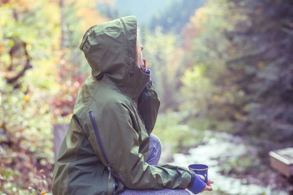 Traveler drink hot tea or coffee in forest in autumn meeting sunrise in mountains — Stock Photo, Image