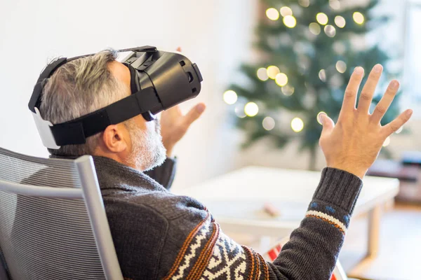 Homem vestindo fone de ouvido realidade virtual sentado em casa — Fotografia de Stock