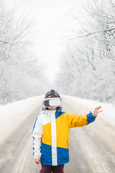 Niño vistiendo gafas de realidad virtual en un paisaje de invierno — Foto de Stock