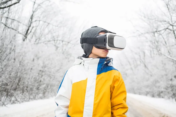 Menino vestindo óculos de realidade virtual em um cenário de inverno — Fotografia de Stock