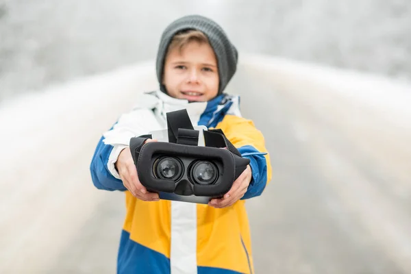 Menino vestindo óculos de realidade virtual em um cenário de inverno — Fotografia de Stock