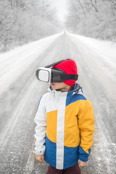 Menino vestindo óculos de realidade virtual em um cenário de inverno — Fotografia de Stock