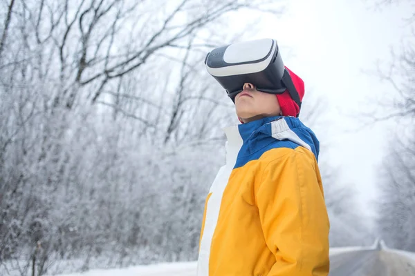 Boy wearing virtual reality goggles on a winter scenery