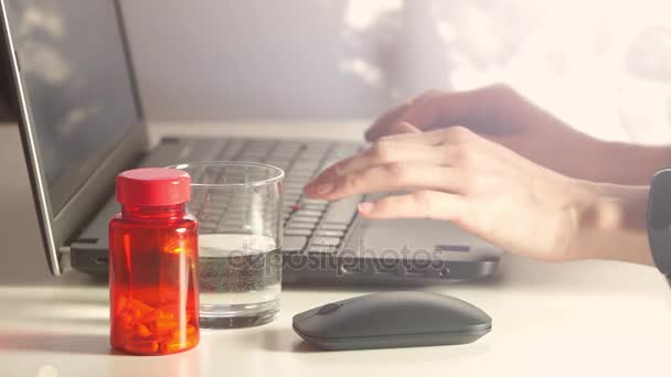Woman taking pill or vitamins while working on laptop — Stock Video
