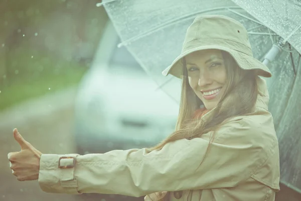 Hitchhiking girl on a road on a rainy day — Stock Photo, Image