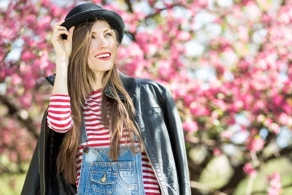 Frühlingsfrau im Blütenpark trägt Hut — Stockfoto