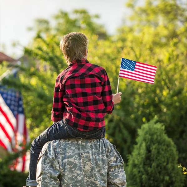 Soldado americano reunido con hijo en un día soleado con bandera americana — Foto de Stock