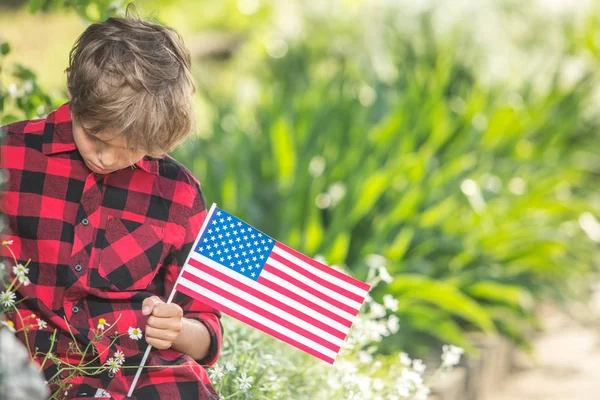 Niño reflexivo con bandera americana sentado — Foto de Stock