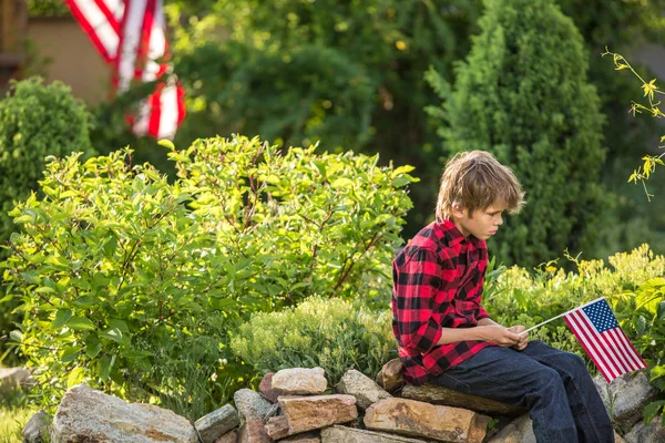 晴れた日にアメリカ国旗を持つ彼の父を待っている少年 — ストック写真