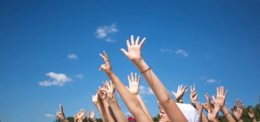 Bir grup mutlu genç insan ellerini havaya kaldırdı.