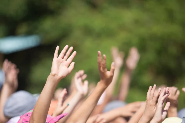 Group of happy young people with hands up to the sky over gre