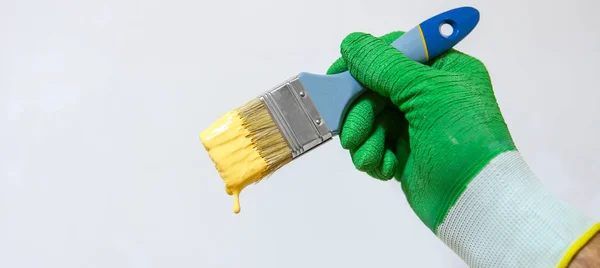 Homem segura escova com tinta amarela — Fotografia de Stock