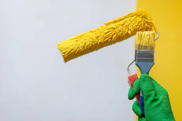 Man houdt rolborstel met gele verf — Stockfoto