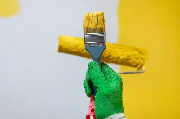 Hombre sostiene cepillo de rodillo con pintura amarilla —  Fotos de Stock