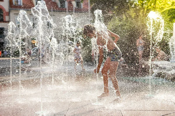 Child playing with water in park fountain
