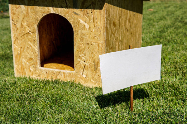 Empty cardboard with wooden dog house on the background