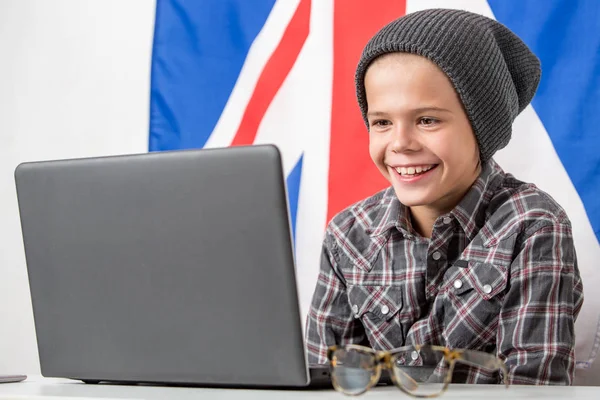 Мальчик на фоне ноутбука с английским флагом на заднем плане — стоковое фото