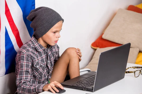 Niño tachonado en frente de la computadora portátil con bandera inglesa en el fondo —  Fotos de Stock