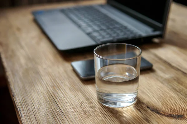 Робочий процес - зображення смартфона, склянки води, верху коліна. вибірковий фокус на склянці води — стокове фото
