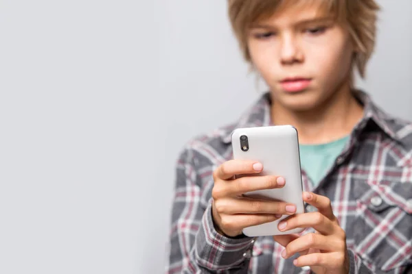 Schattige tiener jongen met behulp van cellphone geïsoleerd over grijs — Stockfoto