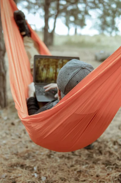 Adam uzun yürüyüşe çıkan kimse rahatlatıcı ve orman Milli Parkı içinde hamakta laptop üzerinde çalışıyor