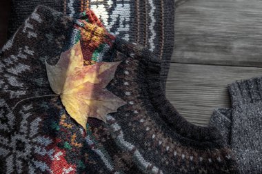 Rahat kazak ve vintage ahşap arka plan üzerinde sonbahar yaprakları 