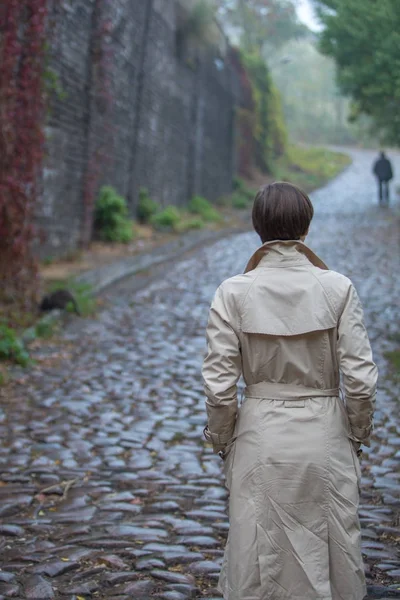 Young woman in beige coat walking on the autumn street — Stock Photo, Image