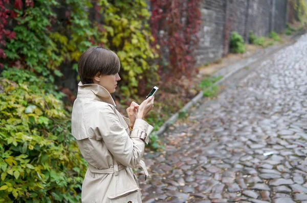 Mujer ocupada con su teléfono móvil mientras camina por una calle de la ciudad —  Fotos de Stock