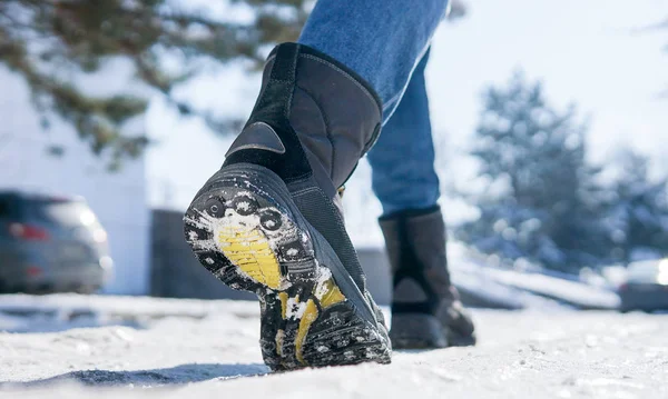 male or female winter boots walking on snowy sleet road