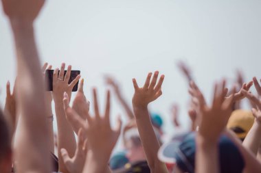 Bir grup mutlu genç insan ellerini havaya kaldırdı.