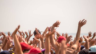 Bir grup mutlu genç insan ellerini havaya kaldırdı.