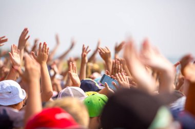 Bir grup mutlu genç insan ellerini havaya kaldırdı.