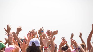 Bir grup mutlu genç insan ellerini havaya kaldırdı.